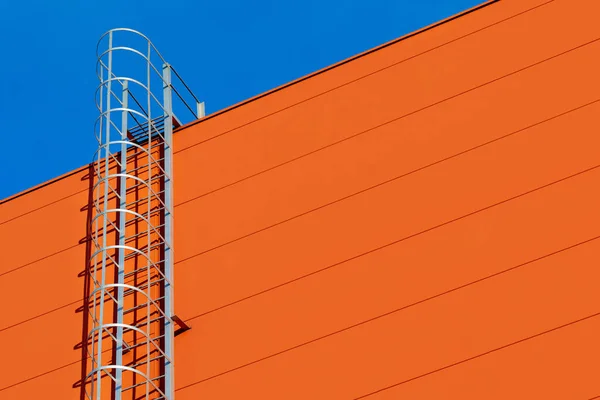 蓝天工业大楼 仓库或购物中心的橙色现代立面的碎片 在蓝天下有长长的金属楼梯楼梯到天堂的象征 复制空间 — 图库照片