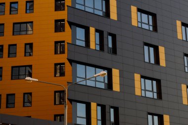 Sarı-kahverengi modern pencereli havalandırmalı cephe. Yeni elit bir konut binasının ya da ticari bir kompleksin parçası. Şehir gayrimenkullerinin bir parçası.