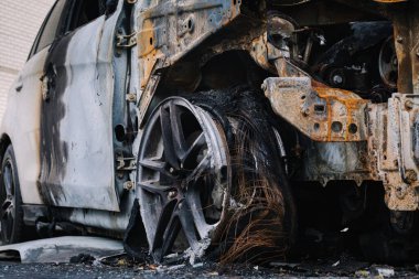 Arabanın lastiği patlamış, gri asfalt yolda. Kundaklamadan sonra evin yakınındaki bir otoparkta arabanın bir parçası. Yangın, haydutluk, sigortalı bir olay, kayıp tazminatı hakkında bir makale göstermek için. Kapat.