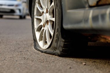 Car wheel with a flat tire on the roadway. Image of an accident, damage, breakdown for illustration on the topic of repair, insurance. Close-up, selective focus. clipart