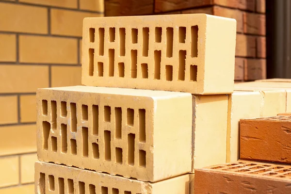 İnşaat alanında bir yığın sarı ve kahverengi tuğla. Kapat.