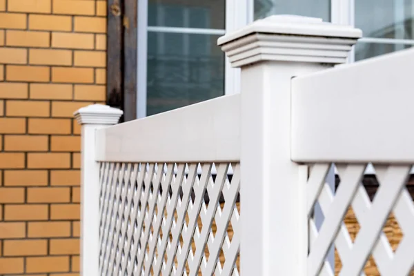 Fragment of a white plastic fence in a modern cottage village. blurred