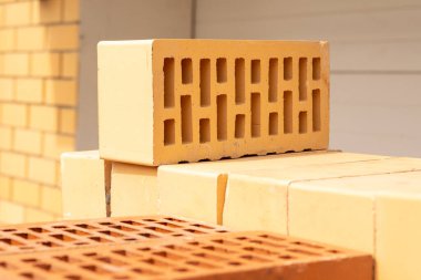 İnşaat alanında bir yığın sarı ve kahverengi tuğla. Kapat.