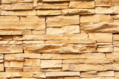 Tahta taşın sarı yüzeyinin dokusu. Duvar dekorasyonu için yapay bitiş taşı blokları. Sert taş arkaplan.