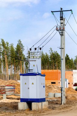 Mobil canlı bir trafo kabini inşaat alanındaki yüksek voltaj direklerinin yanında duruyor..