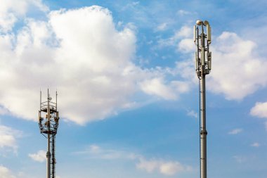 4G, 5G vericili iki telekomünikasyon kulesi. Telekomünikasyon kulesine anten gönderen hücresel baz istasyonu bulutlu mavi gökyüzüne karşı