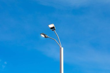 Modern sokak öncü direği mavi gökyüzü arka planında. Şehir elektriği teknolojileri. Cadde yol aydınlatmasında kaydediliyor.