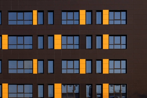 A row of windows on the ventilated facade of a typical modern residential building. Fragment of a new elite residential building or commercial complex. Part of urban real estate.