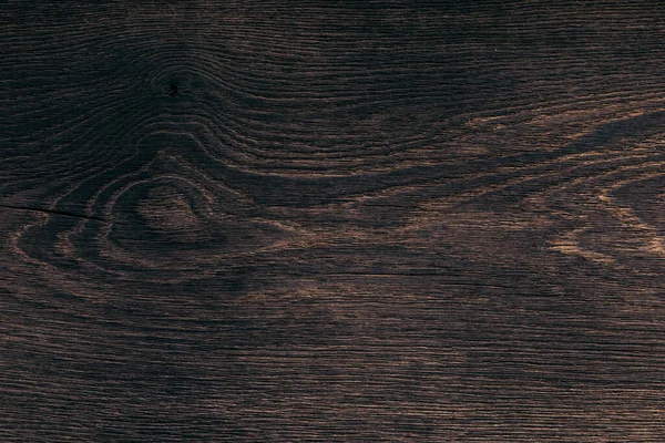 The texture of dark burnt wood with a fibrous uneven structure, places of knots, cracks. Close-up of natural processed Board for furniture production, fence construction