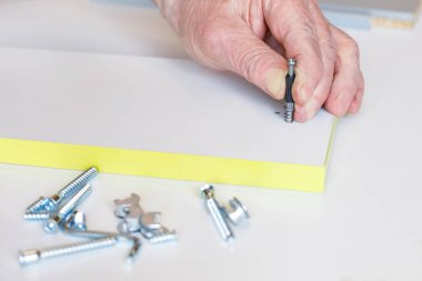 Yaşlı bir adamın eli, mobilya montajı sırasında bağlayıcıyı ayarlar. Yakın plan. Seçici odak.