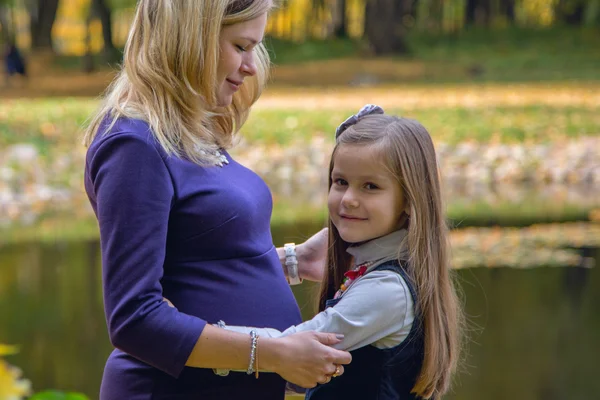 Mãe grávida com filha no passeio no outono Park — Fotografia de Stock