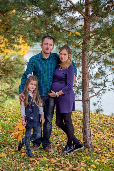 Happy pregnant family in autumn nature — Stock Photo, Image