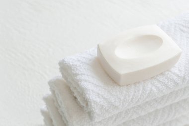 Beyaz arkaplanda beyaz pamuk havlu ve sabun kopyalama alanı.