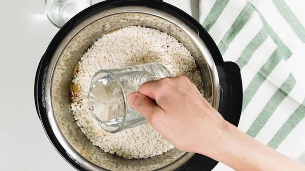 Cooking rice with meat and vegetables  in pressure multi cooker step by step, top view. Pouring water into a pot.