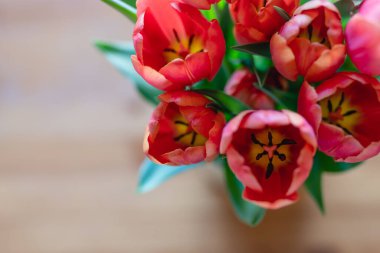 Red tulips bouquet close up on a wooden background, view from above, copy space