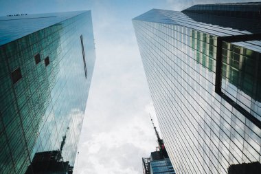 New York City / USA - 24 Mayıs 2019 New York şehri modern mimarisi. Gökdelenler ve bulutlu gökyüzü arkaplanı, düşük açı görünümü.