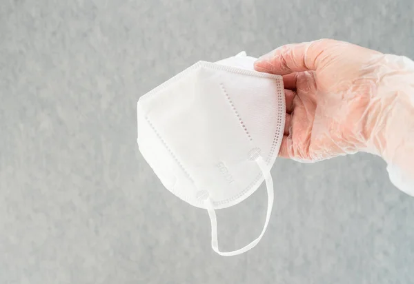 Female hands wearing vinyl gloves  holding KN-95 protection face masks. Close up shot, copy space.  Prevention of the spread of virus and epidemic, protective equipment concept