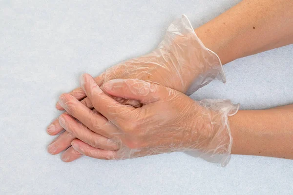 Hands wearing disposable vinyl gloves closeup on grey background, copy space. Protection, health care, medical equipment concept