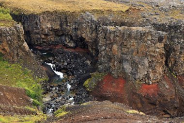 Hengifoss Şelalesi, İzlanda 'nın üçüncü en yüksek şelalesi bazaltik katmanlar arasında kırmızı kil katmanları ile çevrili.