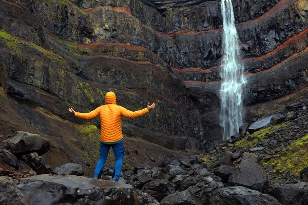 Hengifoss Waterfall, the third highest waterfall in Iceland is surrounded by basaltic strata with red layers of clay between the basaltic layers