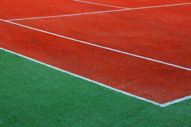 Part of empty used red tennis court playground surface with white lines closeup