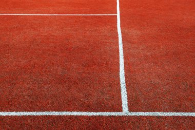Part of empty used red tennis court playground surface with white lines closeup
