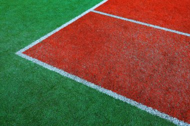 Part of empty used red tennis court playground surface with white lines closeup
