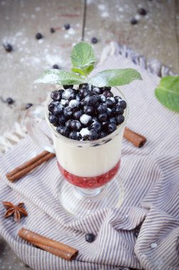 Lezzetli parfe tatlı sufle ve jöle katmanları bilberry ile süt. Rustik ahşap zemin üzerine bir bardak dondurulmuş muamele etmek