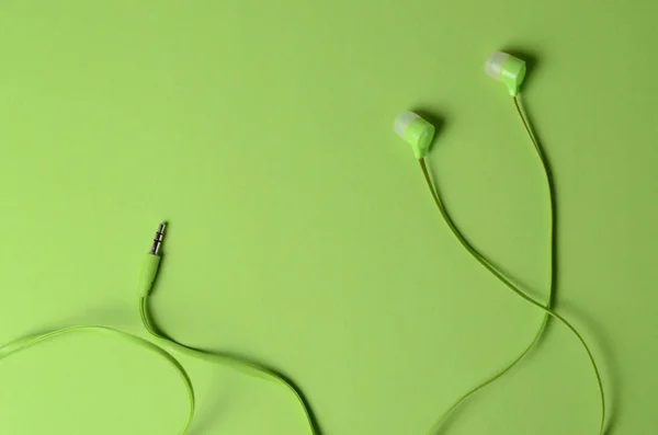 Světle zelená sluchátka pro hráče na podobné zelené pozadí. Černobílé pojetí pro design webových stránek, pohlednice, reklamní. — Stock fotografie
