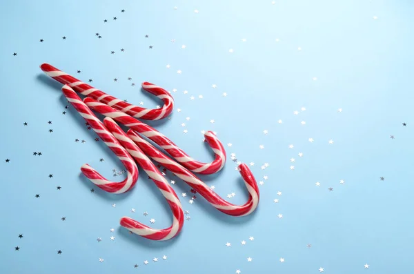Creatieve lay-out gemaakt van lollipop riet en fonkelende sterren. Kerst vakantie achtergrond, minimale s-concept. — Stockfoto