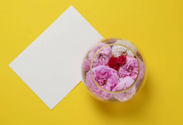 Rosas sobre un jarrón de vidrio, sobre un fondo amarillo. plano yacía bodegón concepto —  Fotos de Stock