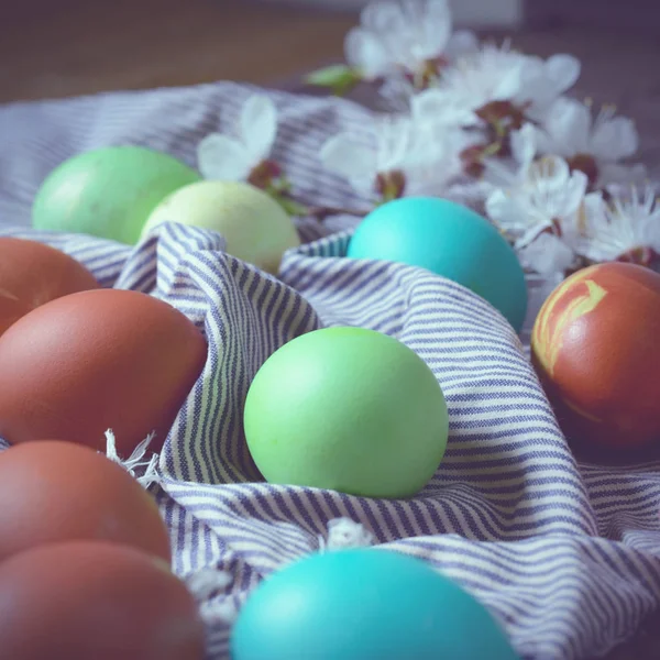 Pasen achtergrond met traditionele gekleurde eieren op een landelijke tafel. Hipster stijl achtergrond voor orthodoxe en katholieke vakantie — Stockfoto