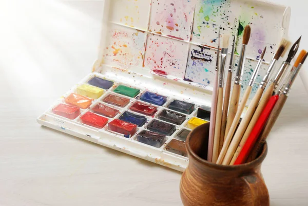 Parlak suluboya boya ve ahşap masa surfase boyama için kullanılan fırçalar. Vintage tonda fotoğraf