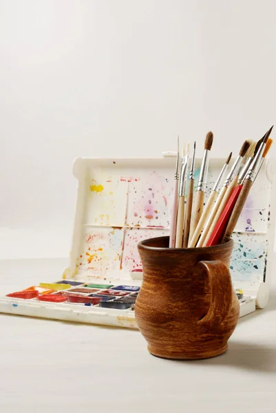 Pinturas de acuarela brillantes y pinceles usados para pintar sobre una superficie de mesa de madera. Vintage tonificado foto — Foto de Stock