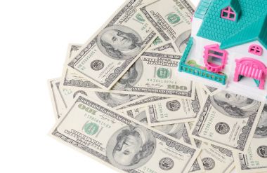 İpotek veya gayrimenkul konsept. Küçük tatil evi ayakta beyaz izole yüz dolar faturaları bol.