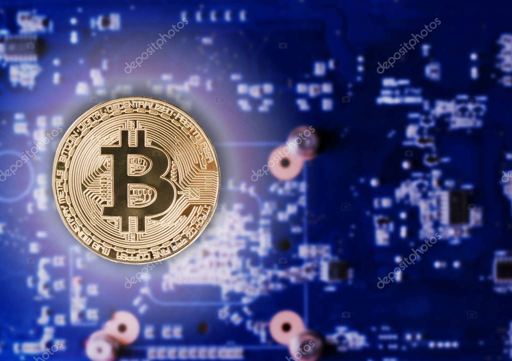 Physical Gold Bitcoin Coin on a computer video card. New independent worldwide cryptocurrency. Bitcoin mining with computer.