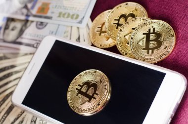 Fiziksel altın Bitcoin para dolar faturaları ve smartphone mor bir arka plan üzerinde karşı.