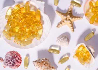 Omega 3 kapsülleri ve uzun gölgeli deniz kabukları. Yedek yiyeceklerin İskandinav balığı yağıyla en üstteki görüntüsü. Vitaminler ve tabletler beyaza karşı.