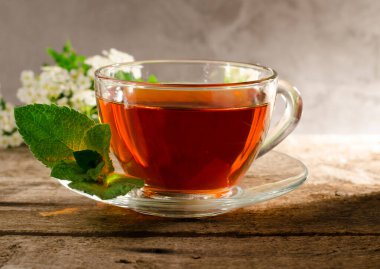 Yasemin çiçekli güzel kokulu çay. Eski ahşap bir masada cam çay fincanı. Fililadelphus çiçekli sıcak içecek.