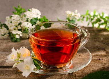 Yasemin çiçekli güzel kokulu çay. Eski ahşap bir masada cam çay fincanı. Fililadelphus çiçekli sıcak içecek.