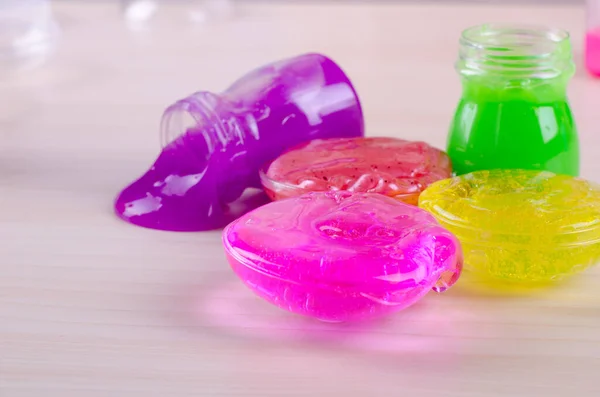 Brillantes limas multicolores en una mesa. Juguete popular para niños de hoy en día. Limo en recipientes de plástico . — Foto de Stock