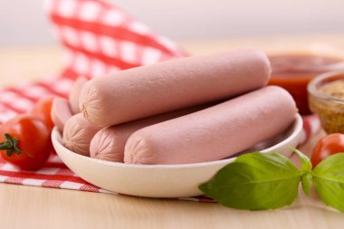 Çeri domatesli kaynamış süt sosisi, ketçap ve dijon hardalı ahşap bir masada..