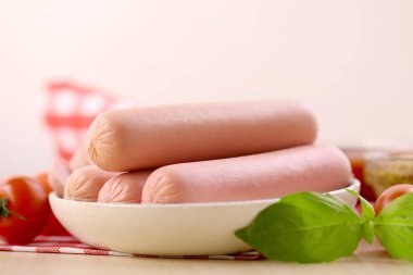 Çeri domatesli kaynamış süt sosisi, ketçap ve dijon hardalı ahşap bir masada..