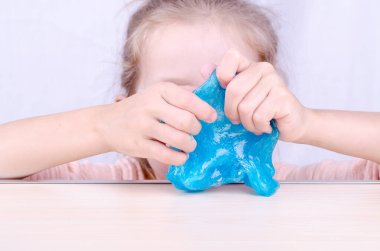 Evde karantinada kalırken bir çocukla oyna, kendi başına balçık yap. Çocuk elinde oyuncak sümüğü. Küçük kız parlak pembe esneme balçığı ile oynuyor. Dünya çapında popüler kendi kendini yetiştirmiş bir oyuncak.