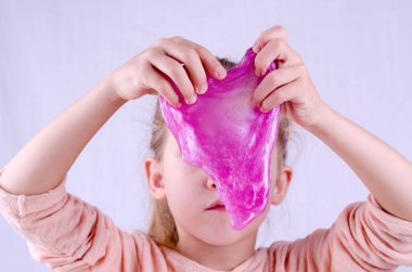 Evde karantinada kalırken bir çocukla oyna, kendi başına balçık yap. Çocuk elinde oyuncak sümüğü. Küçük kız parlak pembe esneme balçığı ile oynuyor. Dünya çapında popüler kendi kendini yetiştirmiş bir oyuncak.