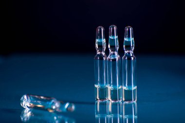 Laboratuvarda laboratuvar mataralarına enjekte etmek için sıvı içeren cam ampuller. COVID-19 arkaplanı.