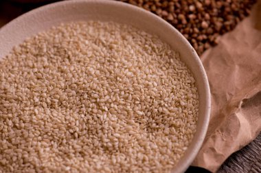 Tahta masadaki bir kasede susam tohumları. Yemek yakın.