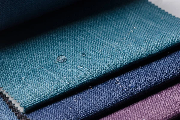 Close up water drop on gunny textile. Concept for easy clean, waterproof surfaces. Multicolor Fabric texture background.