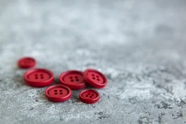 Pile of red matte buttons on concrete background, macro bokeh. beautiful needlework
