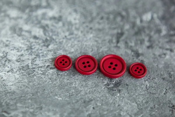 Pile of red matte buttons on concrete background, macro bokeh. beautiful needlework